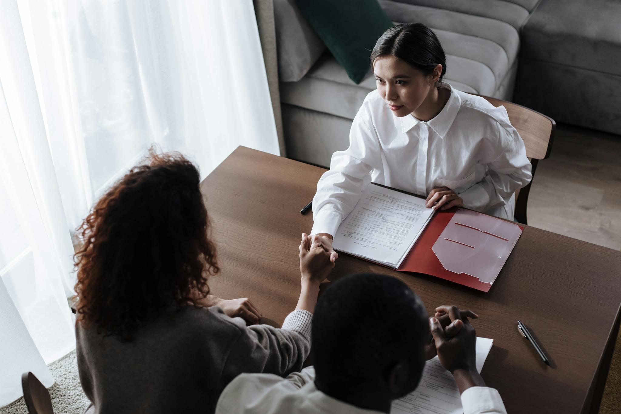 High angle view of business meeting with diverse participants shaking hands over contract.